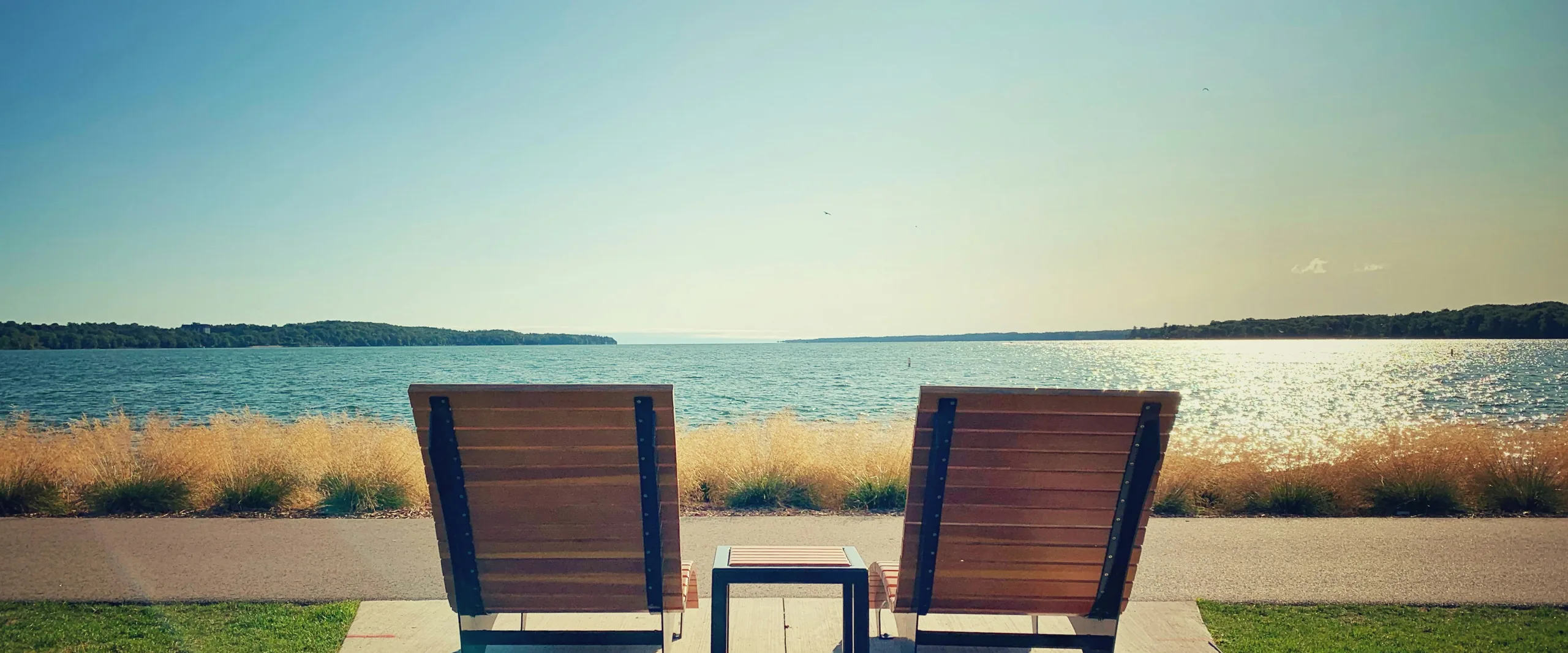 Two wooden lounge chairs facing Kempenfelt Bay on the Barrie waterfront