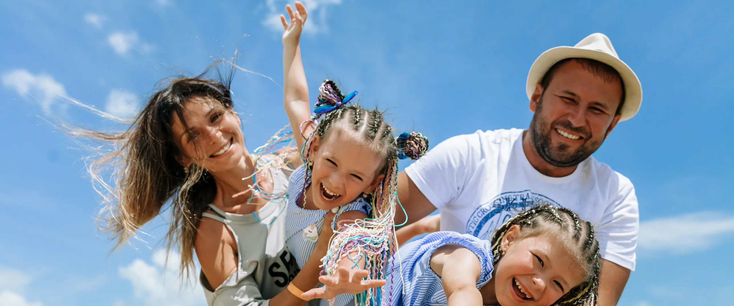 Smiling mother, father and two young daughters laughing together on a sunny beach